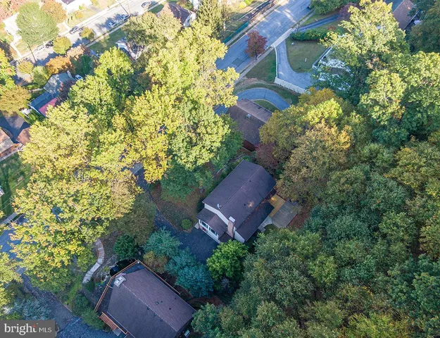 an aerial view of residential house with outdoor space and trees all around