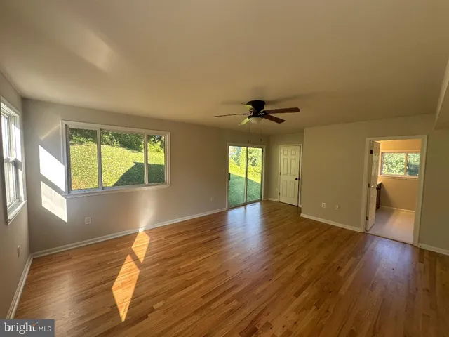 a view of an empty room with wooden floor and a window