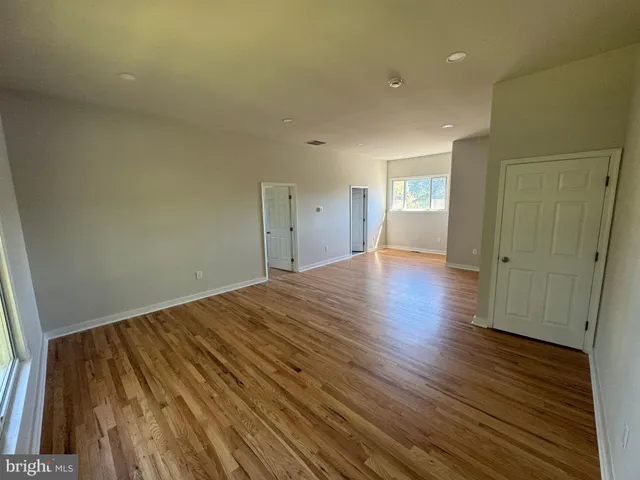 a view of a big room with wooden floor and windows