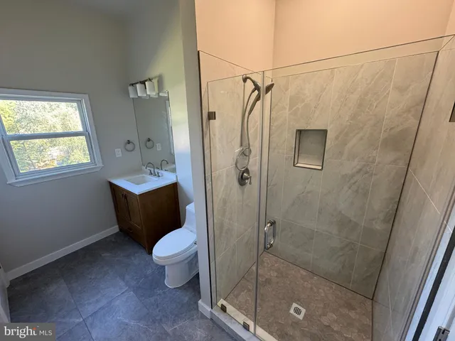a bathroom with a granite countertop sink a toilet and shower
