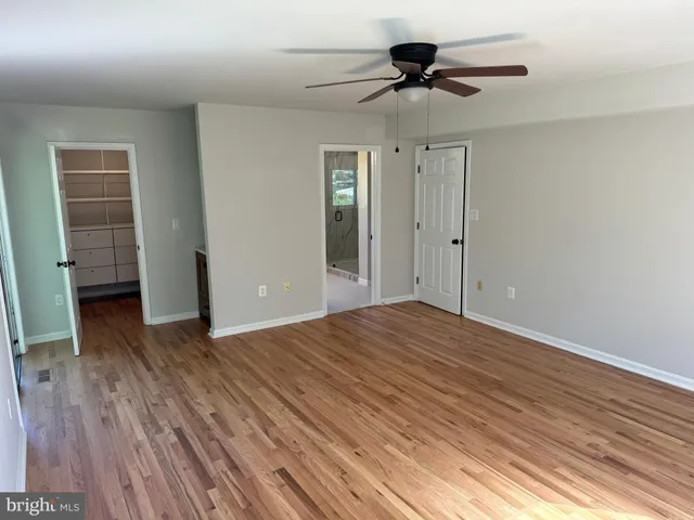 a view of empty room with wooden floor and fan