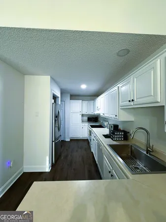 a kitchen with stainless steel appliances a sink a stove a refrigerator cabinets and a counter top space