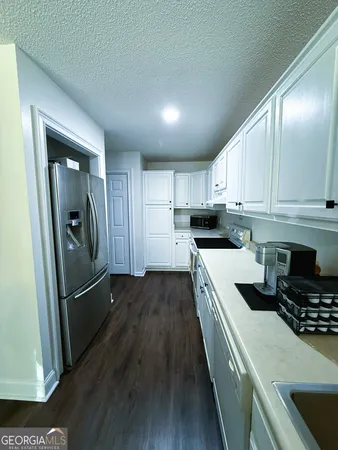 a kitchen with granite countertop a refrigerator a sink a stove and cabinets