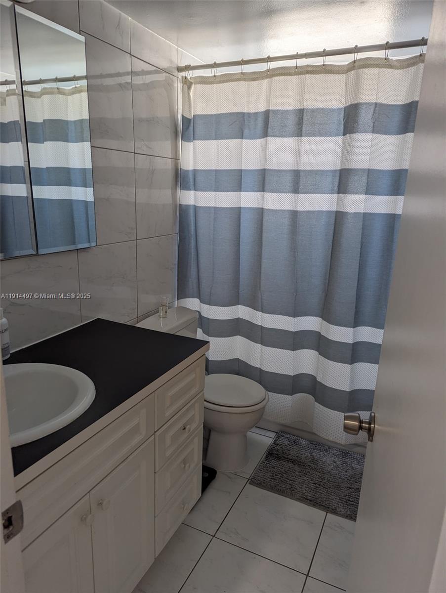 1881 Washington Avenue, Unit 4A Miami Beach, FL 33139 - Photo 11 of 15 a bathroom with a granite countertop sink and a toilet