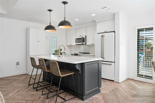 a kitchen with stainless steel appliances a dining table chairs refrigerator and sink