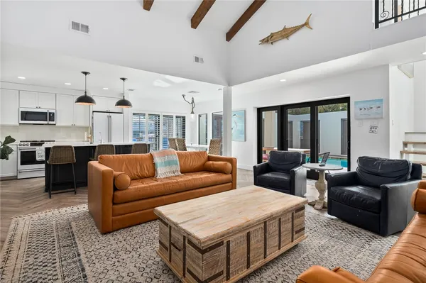 a living room with furniture kitchen view and a chandelier