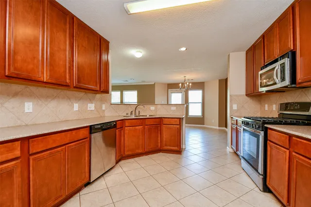 a large kitchen with stainless steel appliances granite countertop a stove a sink dishwasher and a refrigerator with wooden cabinets