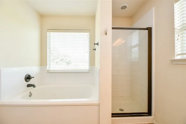a bathroom with a bathtub a shower and a window