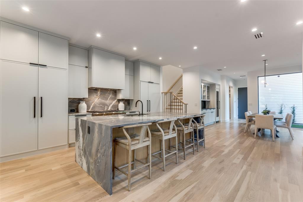 a kitchen with stainless steel appliances granite countertop a table chairs sink and refrigerator