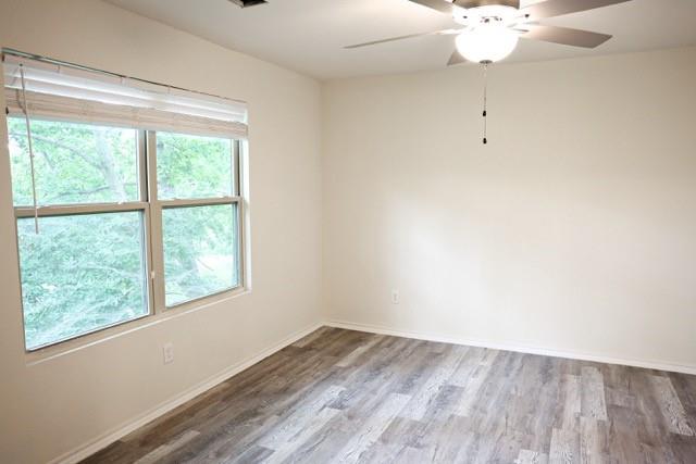 802 South 5th Street, Unit 1 Bonham, TX 75418 - Photo 23 of 25 Bright interior space featuring wood-finish flooring, a contemporary ceiling fan with integrated lighting, and a large window with blinds
