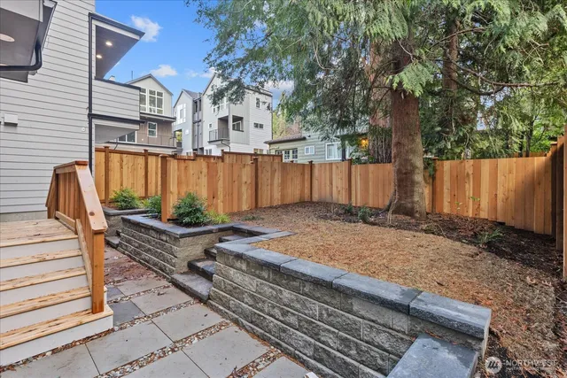 a view of backyard with wooden fence and large trees