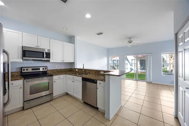 a large kitchen with granite countertop a stove top oven microwave and cabinets