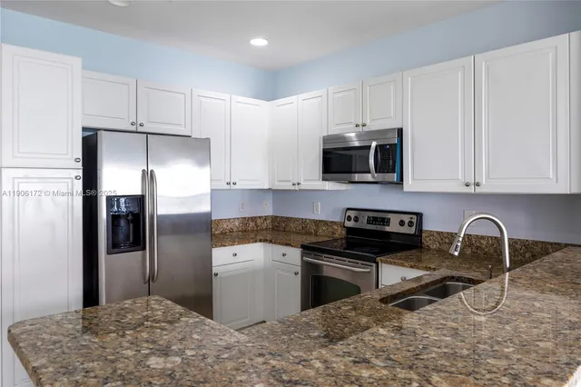 a kitchen with stainless steel appliances granite countertop a stove a refrigerator and a microwave