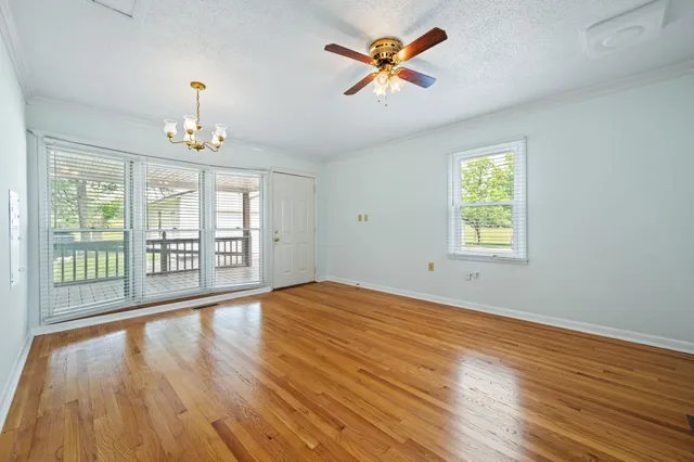 a view of an empty room with a window and wooden floor