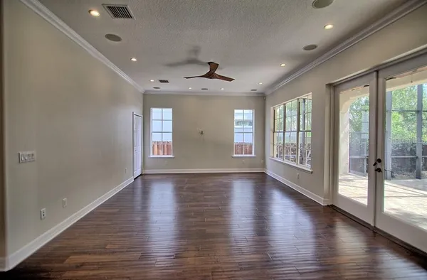 a view of an empty room with wooden floor and a window
