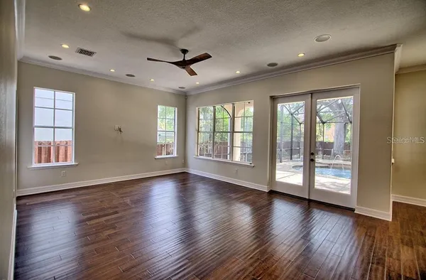 a view of an empty room with wooden floor and a window