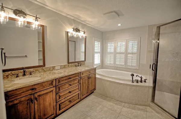 a spacious bathroom with a granite countertop tub sink shower and mirror