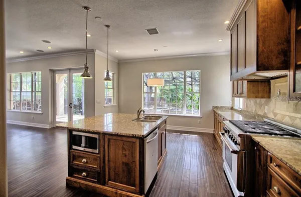 a kitchen with stainless steel appliances granite countertop a stove a sink dishwasher and a refrigerator with wooden floor