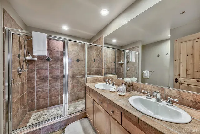 a bathroom with a double vanity sink mirror and shower