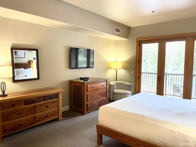 a bedroom with a bed and a flat tv screen on dresser