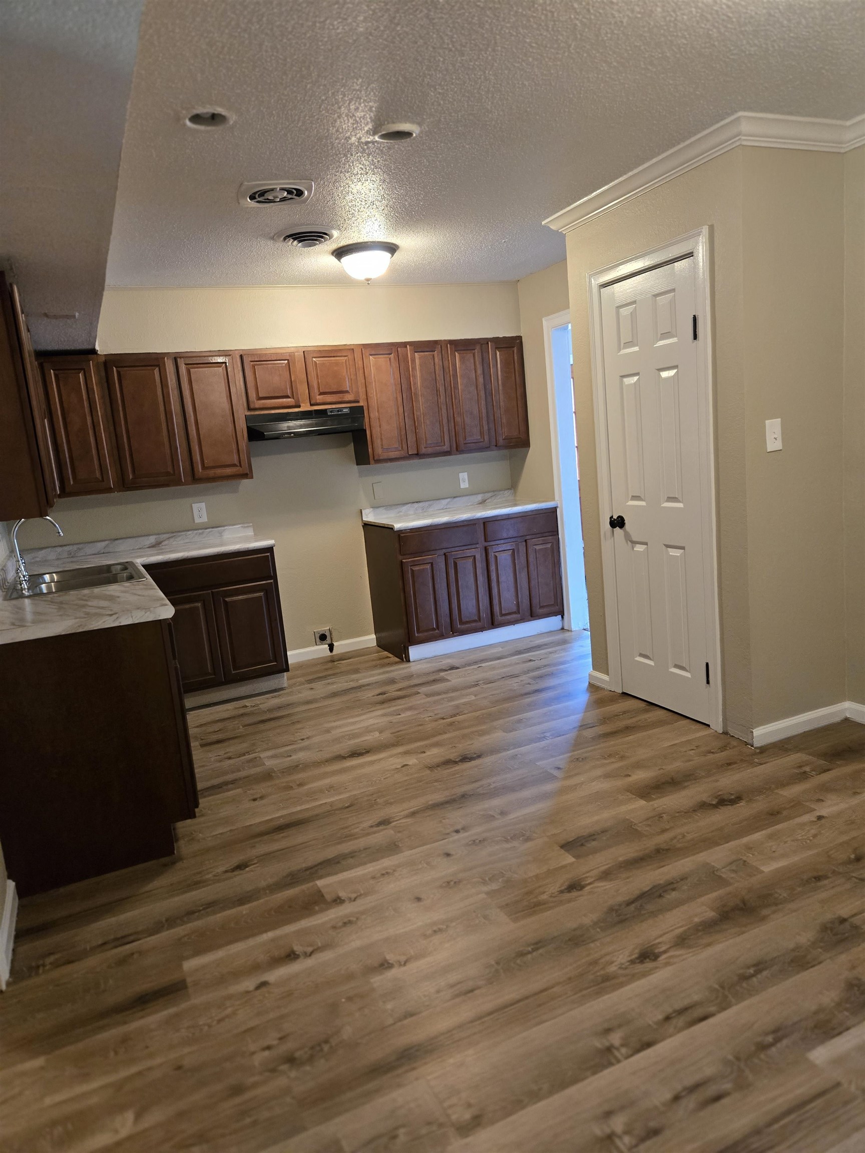 4207 Kenosha Road Memphis, TN 38118 - Photo 11 of 24 Kitchen featuring a sink, baseboards, a textured ceiling, under cabinet range hood, and wood finished floors