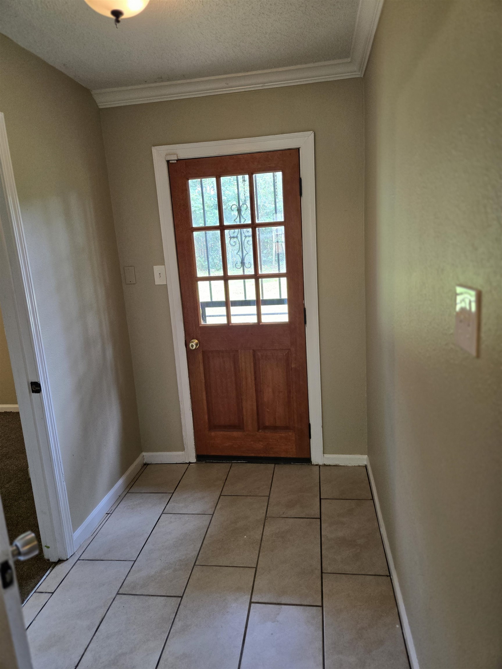 4207 Kenosha Road Memphis, TN 38118 - Photo 23 of 24 Entryway featuring ornamental molding, baseboards, light tile patterned floors, and a textured ceiling