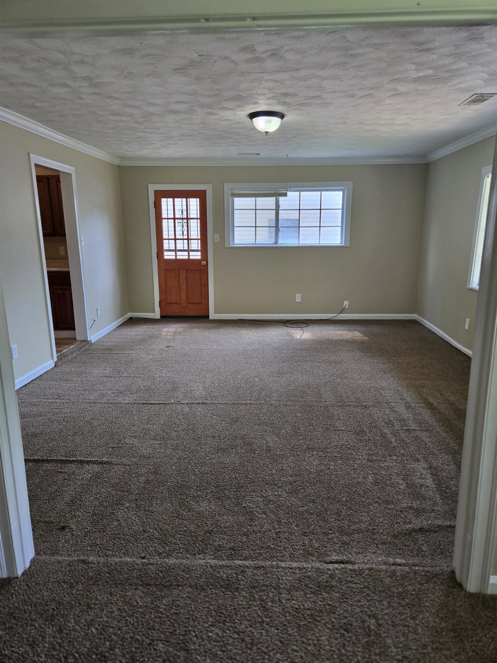 4207 Kenosha Road Memphis, TN 38118 - Photo 7 of 24 Carpeted spare room featuring ornamental molding, baseboards, and a textured ceiling