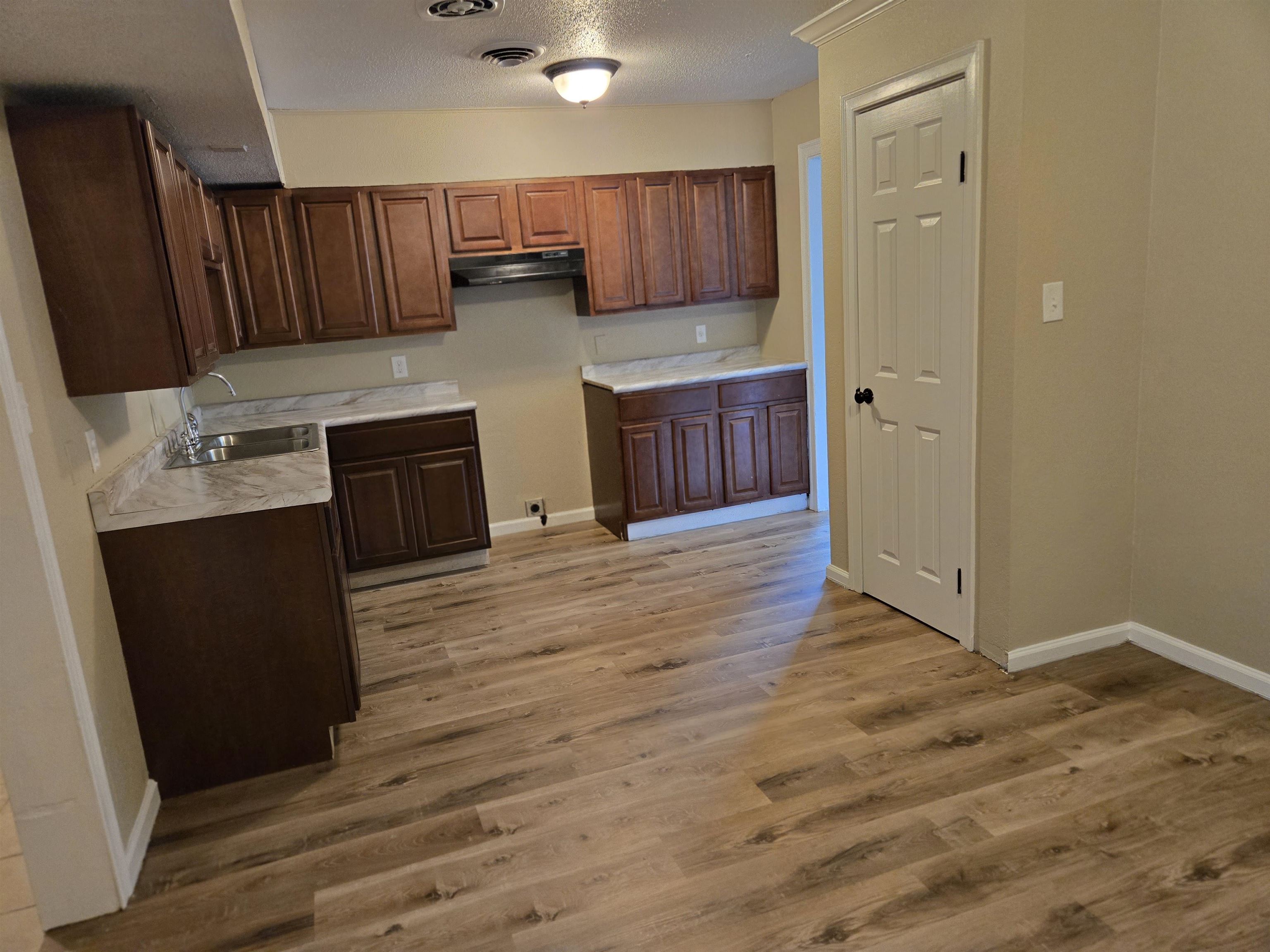 4207 Kenosha Road Memphis, TN 38118 - Photo 8 of 24 Kitchen with a sink, light wood-style flooring, under cabinet range hood, light countertops, and a textured ceiling