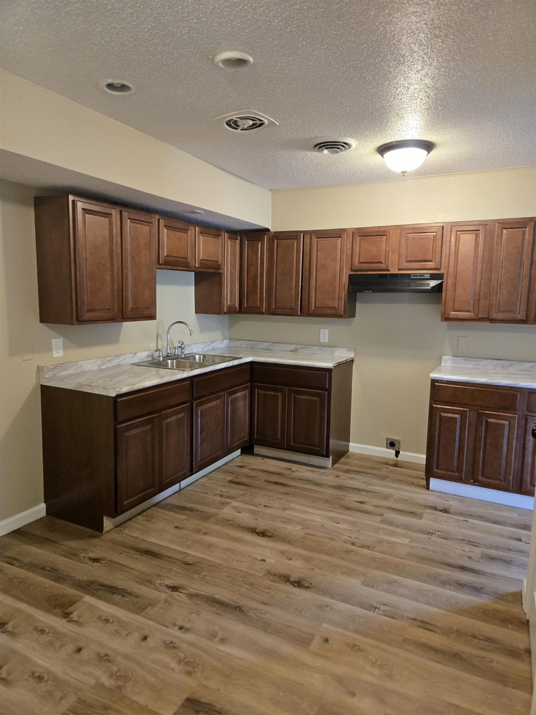 4207 Kenosha Road Memphis, TN 38118 - Photo 9 of 24 Kitchen featuring a sink, a textured ceiling, wood finished floors, baseboards, and light countertops