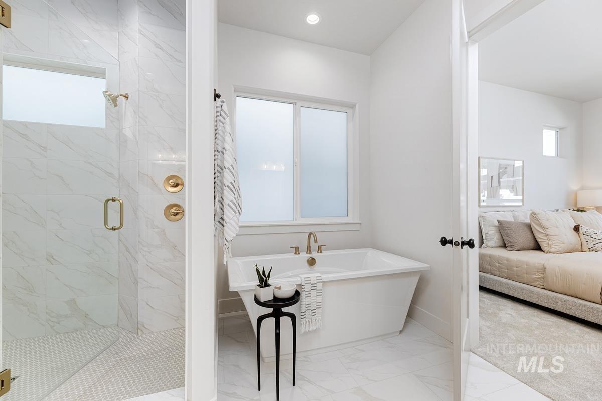 5817 South Gustav Avenue Meridian, ID 83642 - Photo 17 of 33 Freestanding soaking tub with gold-finish fixtures and a tiled walk-in shower with a glass enclosure
