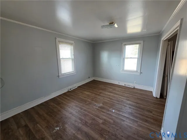 an empty room with wooden floor and windows