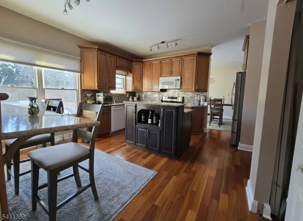 a living room with stainless steel appliances granite countertop furniture wooden floor and a view of kitchen