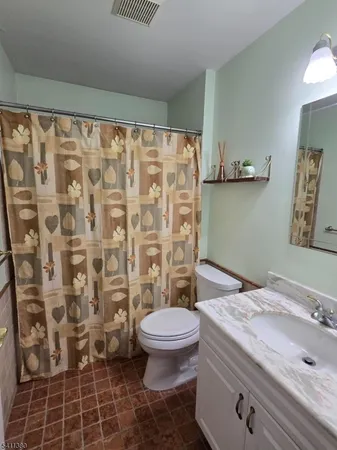 a bathroom with a granite countertop sink a toilet and a shower