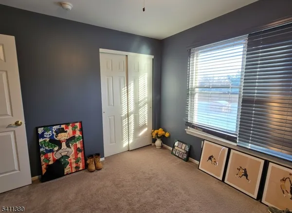 a view of an empty room with window and a kitchen