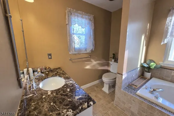 a bathroom with a granite countertop toilet a sink and a mirror