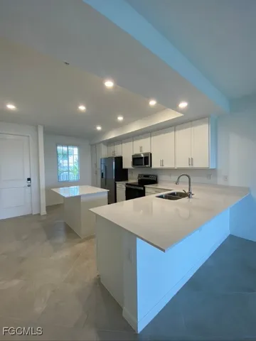 a large kitchen with kitchen island a sink table and chairs