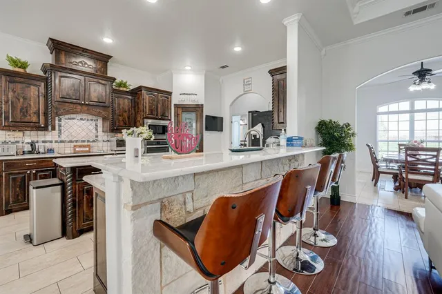 a kitchen with stainless steel appliances granite countertop a stove top oven a sink a dining table and chairs with wooden floor