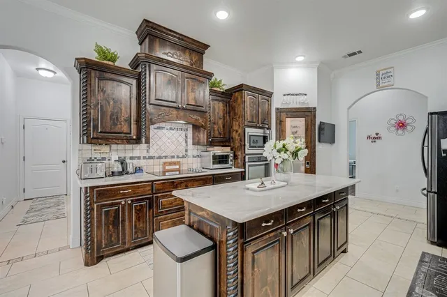 a kitchen that has a kitchen island wooden cabinets and stainless steel appliances