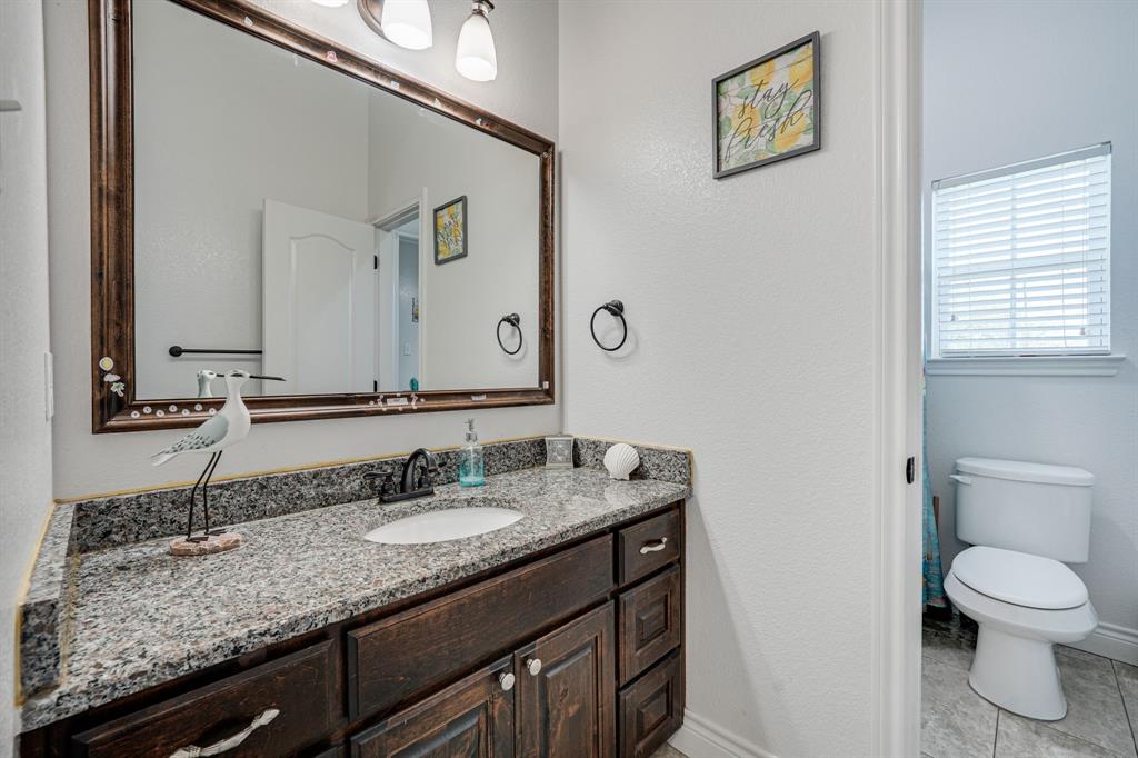1192 Seaborn Road Ponder, TX 76259 - Photo 22 of 40 a bathroom with a granite countertop sink a toilet and a mirror