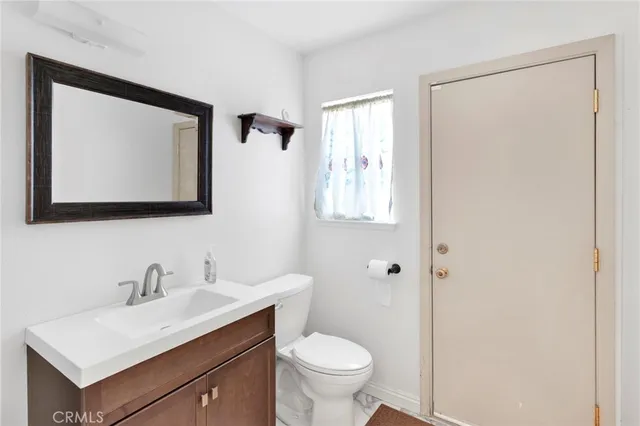 a bathroom with a toilet a sink a mirror and a window