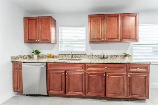 a kitchen with granite countertop wooden cabinets a sink and dishwasher