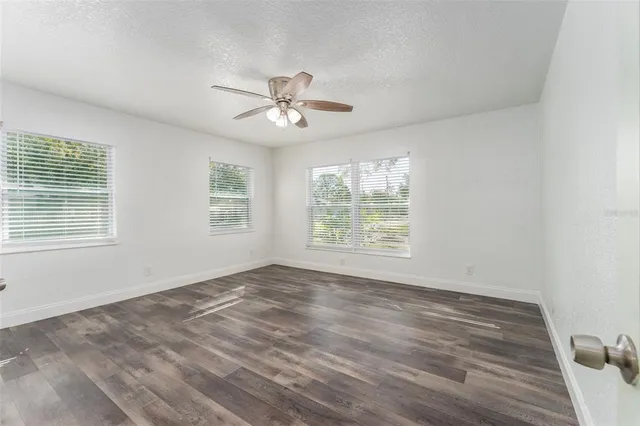 a view of empty room with wooden floor and fan