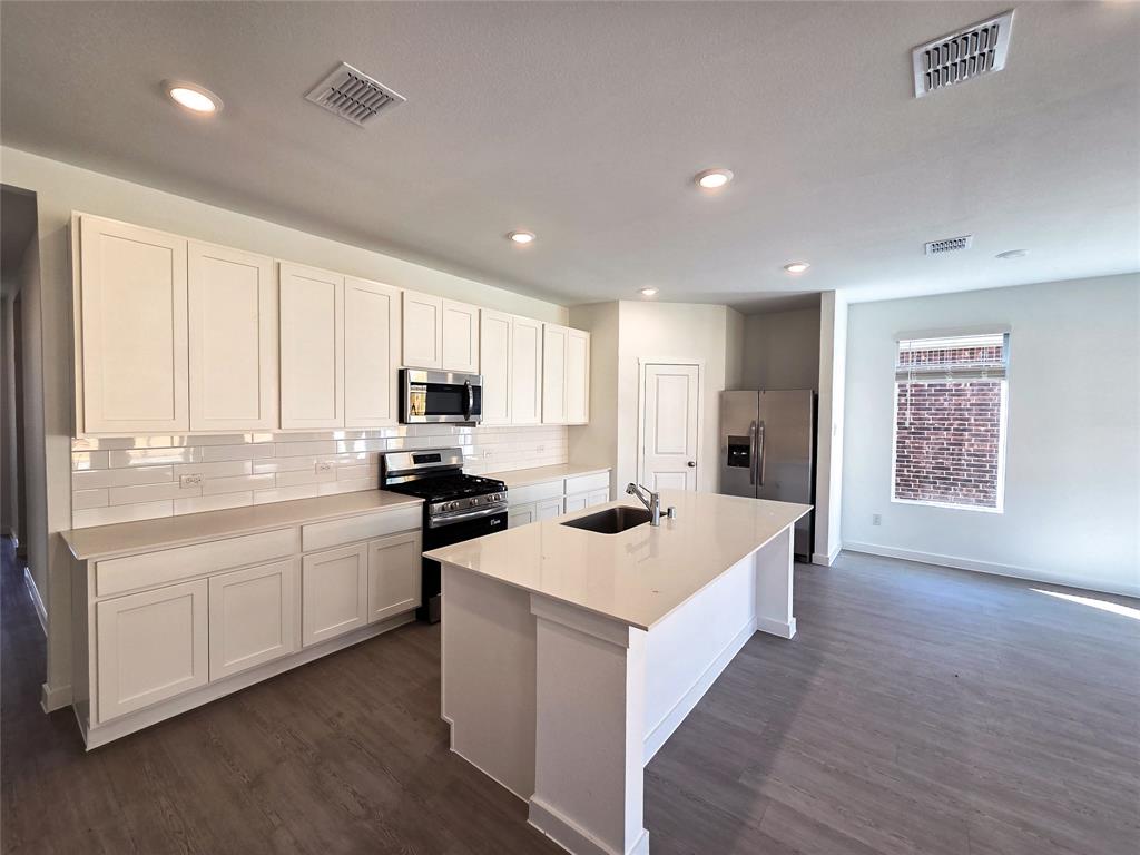 925 Calley Pear Trail Princeton, TX 75407 - Photo 11 of 24 a kitchen with stainless steel appliances white cabinets and wooden floor
