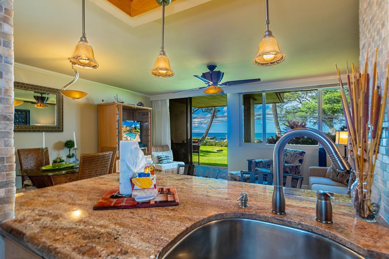 a view of a kitchen with stainless steel appliances granite countertop a sink a stove and a dining table
