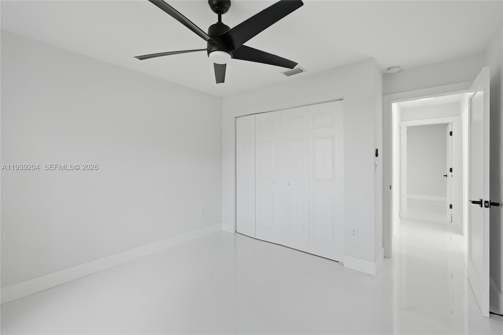 15956 Southwest 83rd Terrace Miami, FL 33193 - Photo 19 of 44 an empty room with a chandelier fan and wooden floor