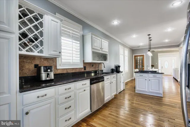 a large kitchen with granite countertop a stove top oven a sink a dining table and chairs with wooden floor