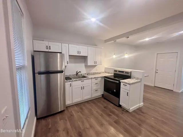 a kitchen with granite countertop a refrigerator stove top oven and sink