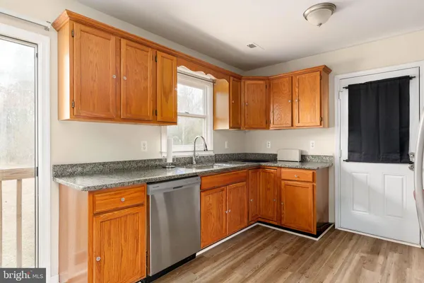 a kitchen with stainless steel appliances granite countertop wooden cabinets a sink and dishwasher with wooden floor