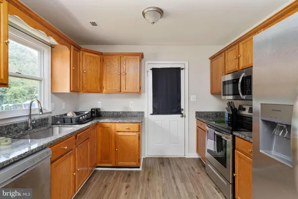 a kitchen with granite countertop a sink wooden floor and stainless steel appliances