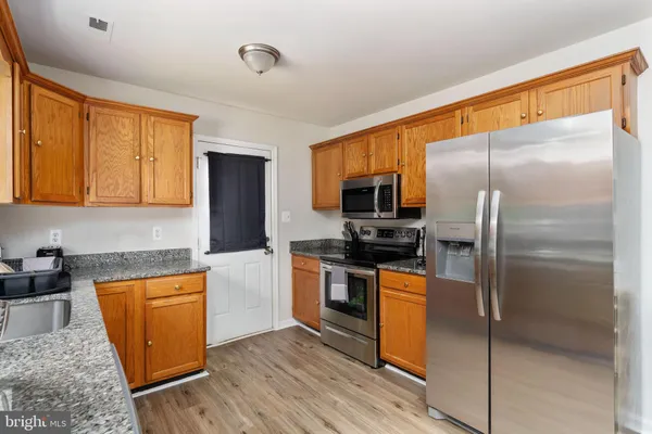 a kitchen with stainless steel appliances granite countertop a refrigerator a stove and a sink with wooden floor